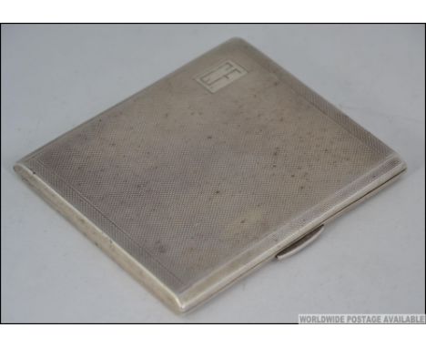 A silver hallmarked cigarette case  with monogram cartouche being engine turned. Hallmarks for Rolason Bros, Birmingham 1940.