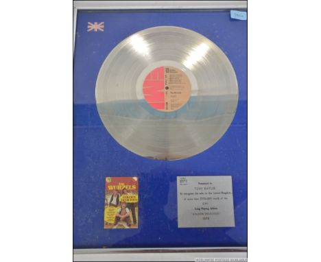 A framed, glazed and mounted Silver disc for The Wurzels ' Golden Delicious '. Presented to Tony Bayliss ( Bass player ) to r
