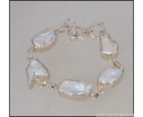 A contemporary silver and baroque pearl bracelet with bar and hoop mount. Marked 925. Length 18cms / 15.9g weight