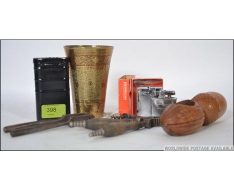 A collection of items to include a treen nut cracker, two other pairs of nut crackers, cork screw and a tinned gun  cleaning 