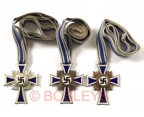 German Third Reich Mother’s Cross 2nd Class and two 3rd Class.The first a good silvered example with blue and white enamelled