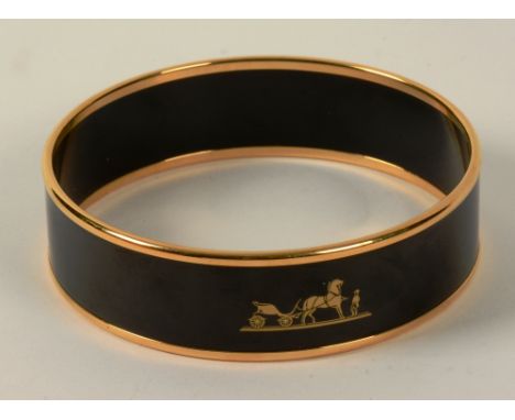 A Hermes black enamel bangle, with gold plated rim to top and bottom, Hermes horse and cart emblem to front and 'Hermes Paris