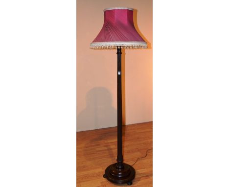 A mahogany floor lamp with shade, ending in circular foot, 186cm high