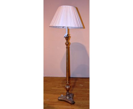 A gilt floor lamp with shade, raised on platform base, 181cm high