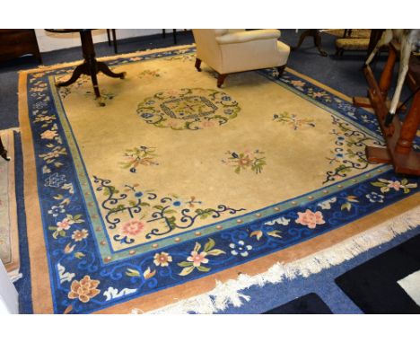 A Chinese type carpet, with floral motifs on mustard ground with blue border, 276cm wide x 357cm long