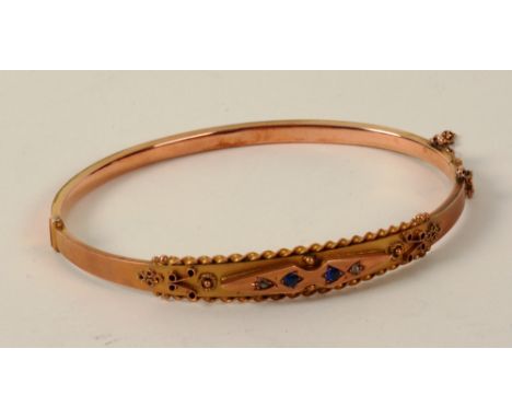 A 9ct gold sapphire and diamond bangle, the two central round cut sapphires flanked by two small old cut diamonds, within fol