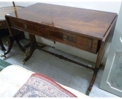 A modern Regency style mahogany finished sofa table, the top with a crossbanded border, over two in-line drawers and opposing