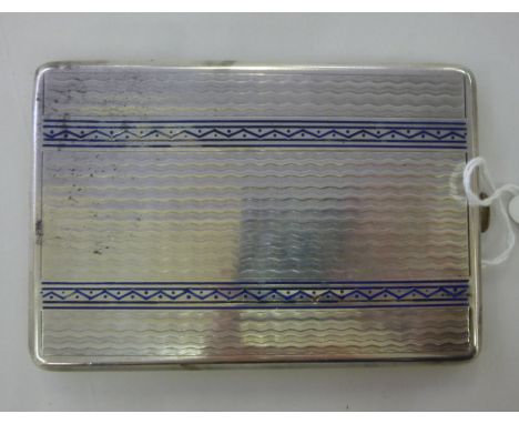 A French silver coloured metal folding cigarette case with engine turned and patterned blue enamelled decoration, on a button