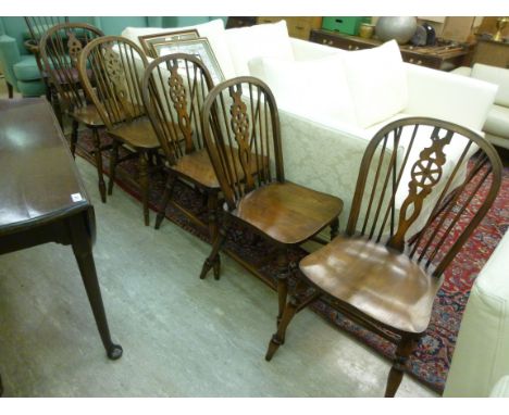 A set of four modern beech and elm framed Windsor, hoop, stick and wheelback chairs, the solid wedge back seats raised on rin