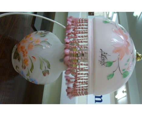 A 1950s French opaque pink glass table lamp with a tasselled, bead bordered dome shade, overpainted with floral designs, bear