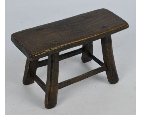 A small rustic oak stool/miniature table with stretchered supports, top 25 x 9cm, height 15cm.