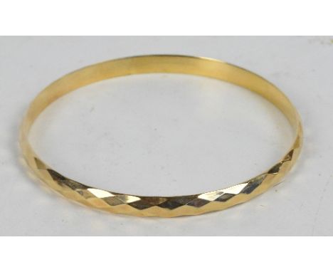 LAWSON WARD & GAMMAGE; a 9ct gold bronze core lagarmic bangle with faceted decoration, diameter 8.5cm, cased.