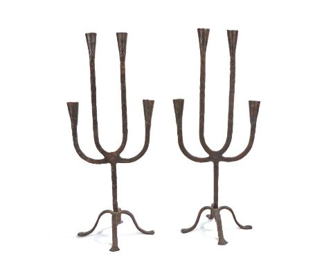                         A pair of wrought iron candelabra, each with four arms with conical socket, on a tripod base, 53cm hi