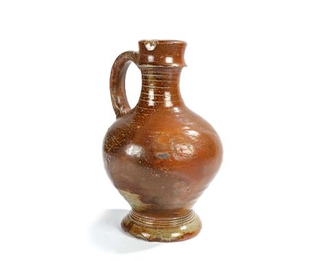 
    
        
            A 17th century stoneware jug, with a brown speckled body above ring decorations and foot, restorat