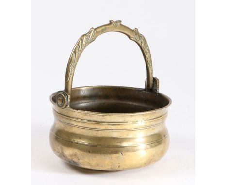 A 17th Century brass stoup, with a swing dolphin handle above the ring turned body, 16cm diameterHandle with brass washer to 