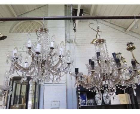 A pair of twelve light crystal electroliers, the lights on two tiers with scroll arms and pendant swags on baluster stems, 58
