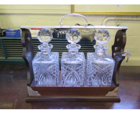 A mahogany and silver plated three decanter tantalus set, 39cm wide