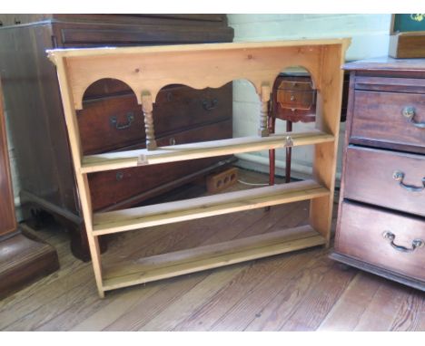 A pine shelf unit, the arcaded top with turned supports over three shelves