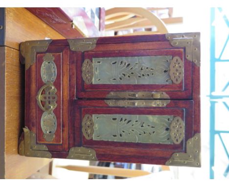 A Chinese hardwood and brass bound table cabinet, with pierced green jade panels, the cupboard doors enclosing four drawers a