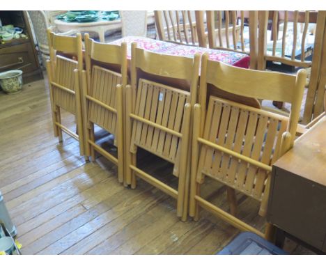 A set of four folding light wood dining chairs