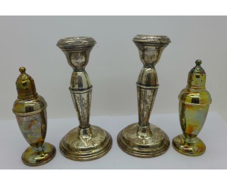 A pair of sterling silver peppers and a pair of sterling silver candlesticks, one candlestick a/f, the peppers marked Reed &a