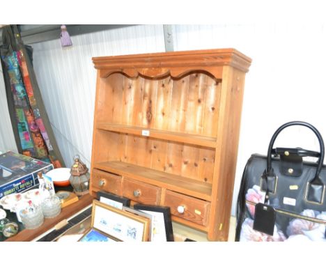 A pine wall shelf fitted three drawers