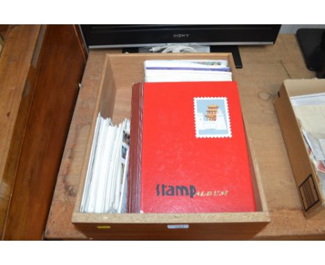 A box containing First Day covers and an album of stamps