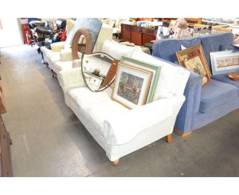 A cream two seater sofa together with two matching armchairs