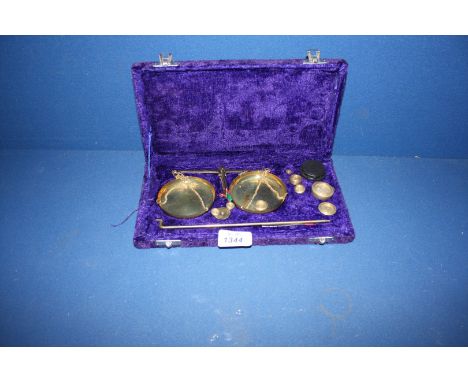 An Apothecary's Scales with weights in a purple velvet case.