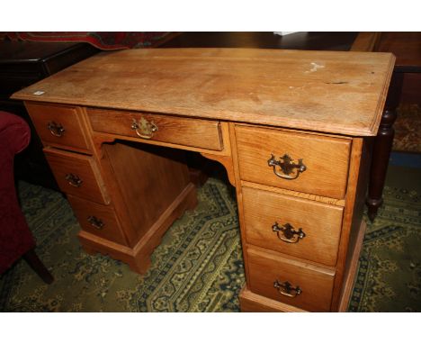 A 1930's light Oak Kneehole Desk, moulded edge rectangular top over central long frieze drawer flanked by two flights of thre