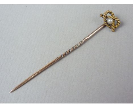 A Victorian yellow-metal stick pin, the terminal modelled as a knotted rope centrally set with a seed pearl, stamped 15ct, te