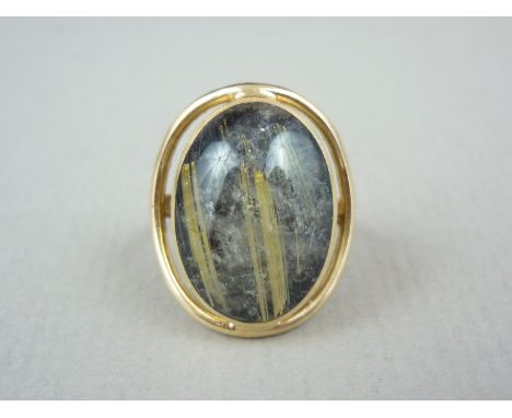 A contemporary rutilated or 'angel hair' quartz cocktail ring, the oval cabochon rub set and held within an annular frame, on