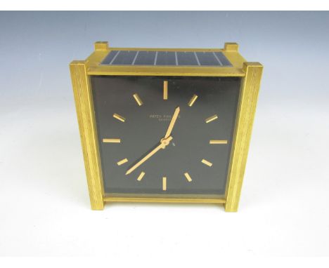 A Patek Philippe solar powered desk clock, quartz movement, square face and black dial with faceted baton markers, in a brush