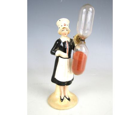 An early 20th Century novelty porcelain egg timer modelled as a waitress, 12.5 cm