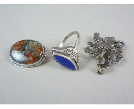 Three vintage white metal brooches, including a moss agate cabochon, rub set and held in a rope frame, a lapis lazuli dress r