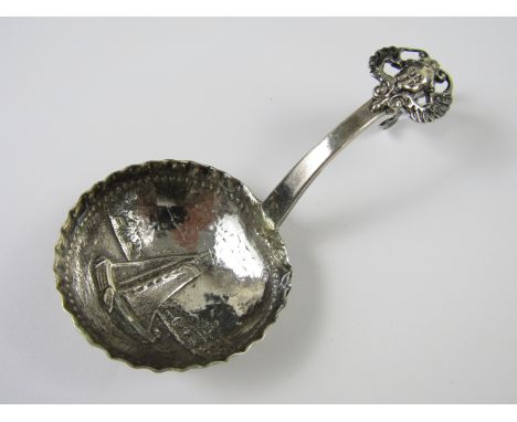 A Dutch silver caddy spoon, the bowl repousse-worked with a vignette incorporating a sail boat, London import marks for 1927,