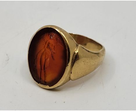 A 9ct. gold carnelian signet ring, hallmarked London 1980, the rub over set oval carnelian intaglio carved with a standing fi