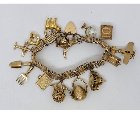 A gold charm bracelet, the 9ct. gold gate bracelet with heart padlock clasp suspending 12 x 9ct. gold charms and 1 x unmarked