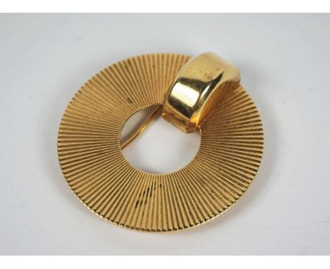 An Art Deco gold sun brooch, signed CARTIER, and marked 14K, of circular form, with engine turned sun burst rays and central 