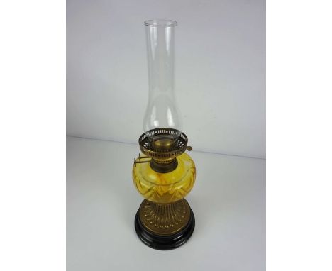A Victorian brass and yellow glass oil lamp, with reeded spreading foot on a black ceramic foot, 55cm high