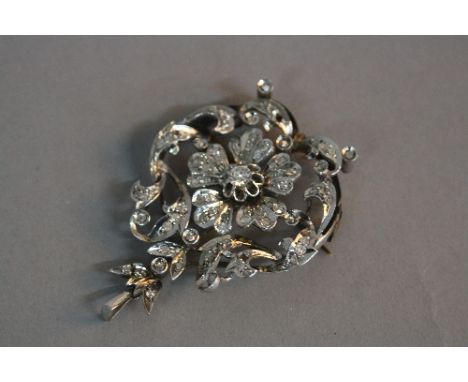 AN EARLY 20TH CENTURY DIAMOND BROOCH PENDANT, a fancy floral and scroll open work design, centring on a transitional brillian