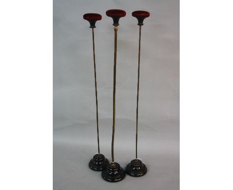 A SET OF THREE LATE VICTORIAN WIG OR HAT STANDS, burgundy velvet and ebony domed top on a brass finish stand with circular bl