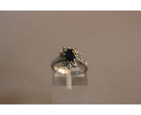 A MODERN PLATINUM SAPPHIRE AND DIAMOND OVAL CLUSTER RING, one oval mixed cut blue sapphire measuring approximately 7mm x 5mm,