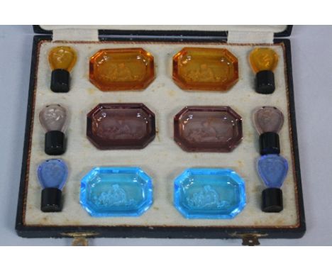 A CASED SET OF ART DECO COLOURED INTAGLIO GLASS, comprising six pin dishes and six stoppers, each with a classical scene, two
