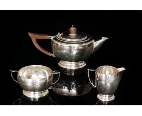 A hallmarked silver three piece tea service comprising of teapot, cream jug and twin handled sugar bowl, each of plain compre