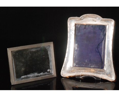 Two hallmarked silver easel back photograph frames, one of tapered, shaped rectangular outline with ribbon tied reeded border