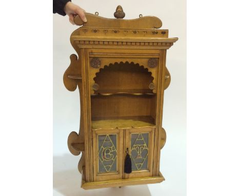 An early 20th Century oak wall hanging smokers cabinet with acorn shaped finial and fret-cut gallery above an alcove and pair