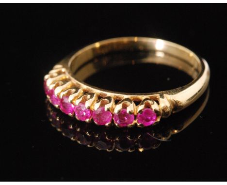 An 18ct ruby seven stone ring, uniform claw set stones to plain shoulders, ring size L. 