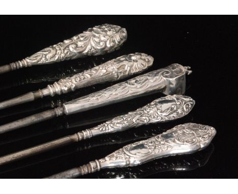 Five Victorian and later hallmarked silver button hooks, each with embossed decoration, various designs to include a foliate 