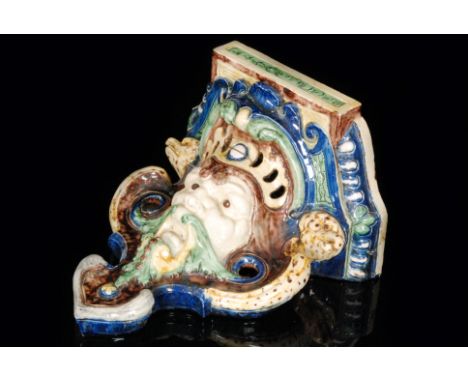 A late 19th Century Continental majolica wall bracket modelled as a bearded male with serpents to the sides, length 32cm, A/F